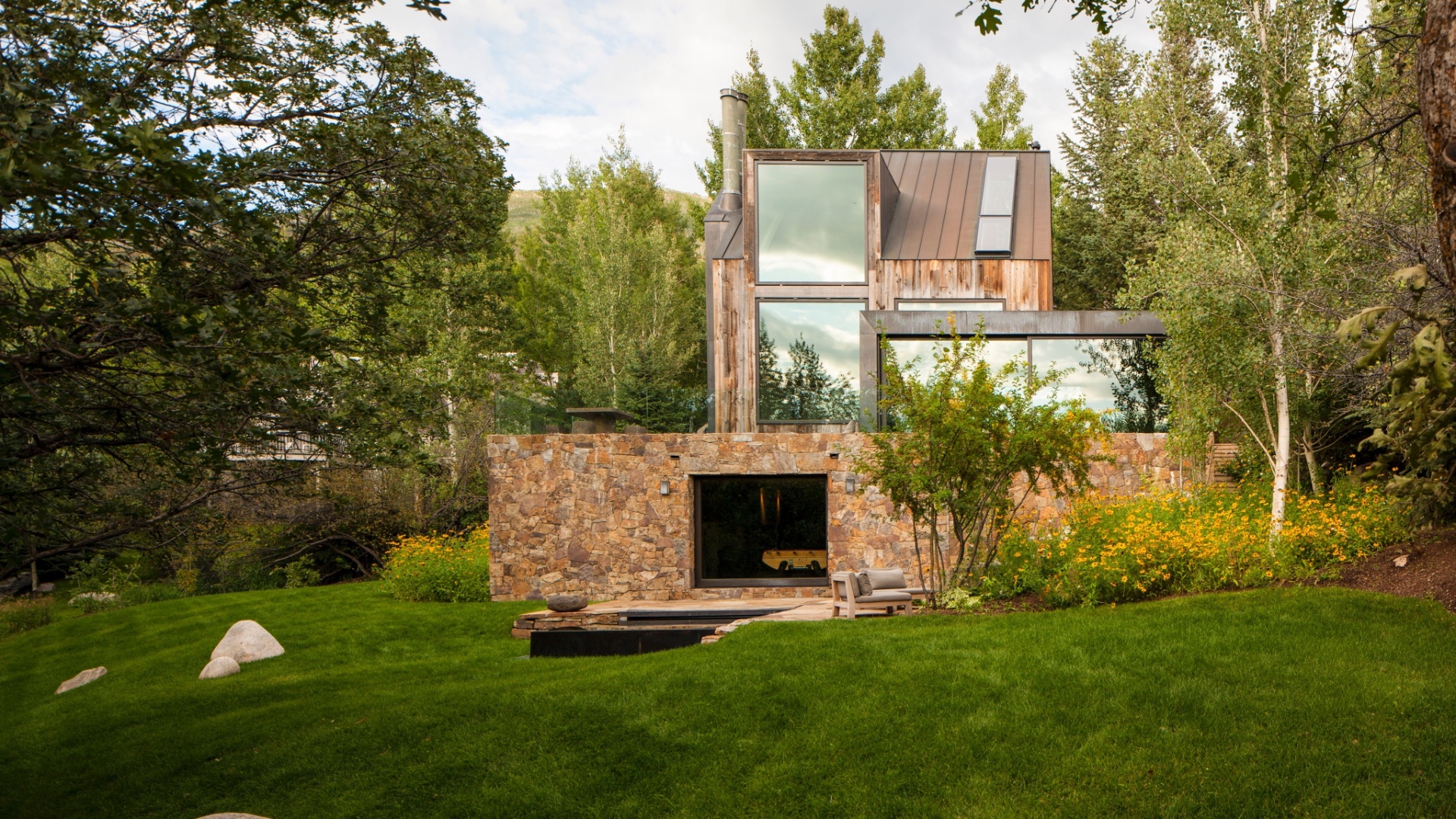 Em vez de competir com a paisagem, Chad Oppenheim projetou uma reforma para a casa construída nos anos 1970 que a fundisse e complementasse a natureza em redor. Assim, a construção foi revestida por pedras extraídas localmente, bem como por madeira, e ganhou amplos janelões de vidro  (Imagem do NYT, usar apenas no respectivo material) - Robert Reck/ The New York Times