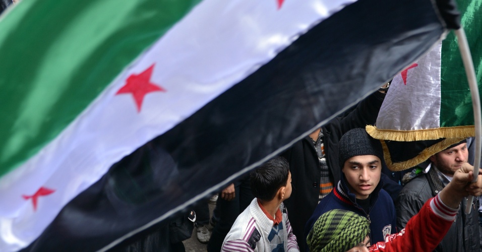 8.fev.2013 - Manifestantes antirregime erguem bandeiras durante protesto no distrito de Bustan al-Qasr, ao norte da cidade de Aleppo, na Síria, nesta sexta-feira (8)