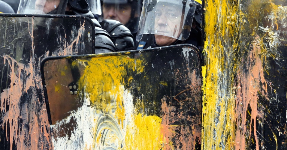 12.fev.2013 - Tropa de choque da polícia francesa é atingida por tinta e ovos jogados por manifestantes contrários aos planos de fechar a fábrica da Goodyear no país