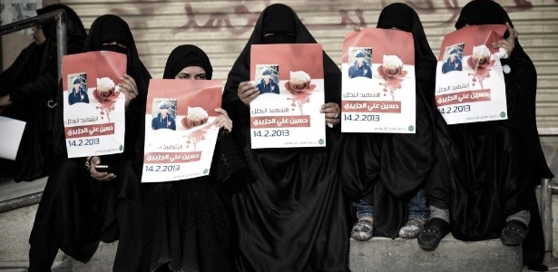 Mulheres da cidade de Daih, no Bahrein, seguram cartazes com a foto de Hussein al-Jazeeri, adolescente de 16 anos morto por forças barenitas durante protestos pelo segundo aniversário de um levante para exigir reformas democráticas