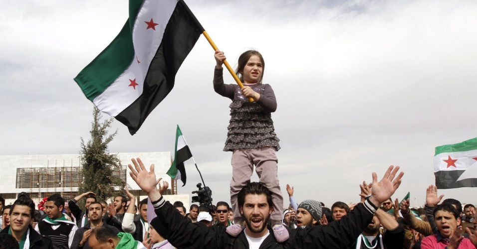 22.fev.2013 - Menina segura uma bandeira da Síria sobre os ombros de seu pai, durante protesto contra o regime do presidente Bashar al Assad, em frente à embaixada síria na Jordânia