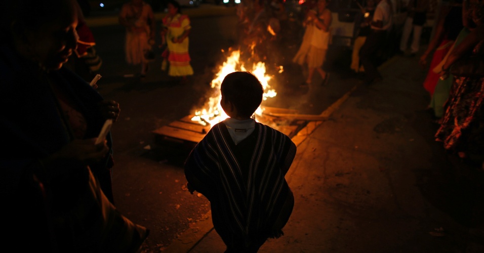 22.fev.2013 - Criança dança batuque indígena ao redor do fogo durante uma cerimônia realizada no centro de Caracas, em Venezuela, em homenagem ao presidente venezuelano, Hugo Chávez, que se recupera de uma cirurgia de câncer. O político, segundo informações oficiais, ainda apresenta problemas respiratórios