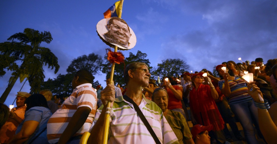 22.fev.2013 - Homem segura uma foto do presidente venezuelano, Hugo Chávez, durante missa realizada ao ar livre no centro de Caracas, na Venezuela, em homenagem ao político que se recupera de uma cirurgia de câncer