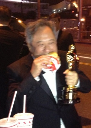 Após a cerimônia do Oscar, Ang Lee deixou de lado as festas glamourosas e foi à rua comer um lanche, sem desgrudar da estatueta - Reprodução/Twitter