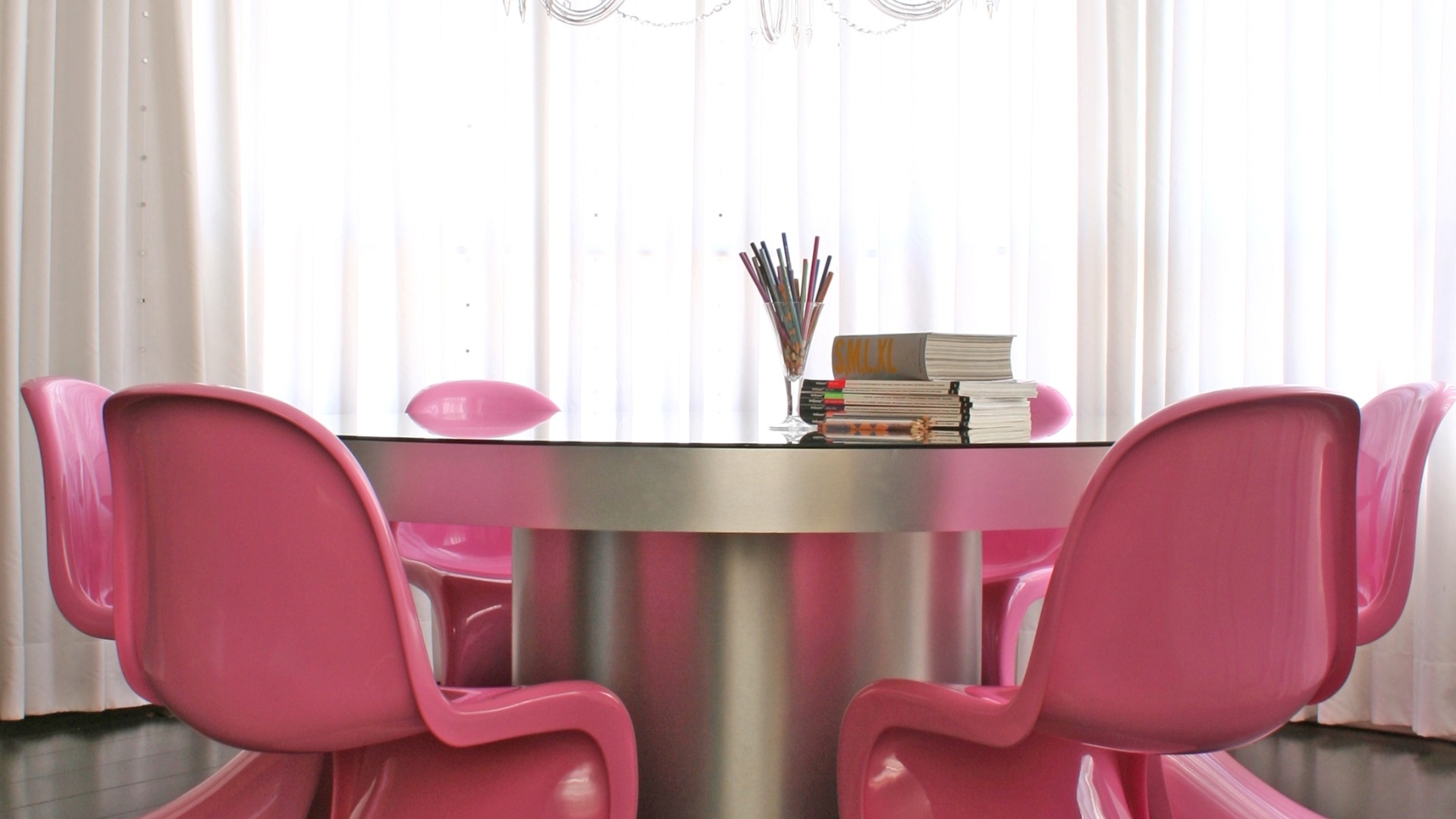 Para o projeto de decoração de um apartamento em Londrina (PR),  o arquiteto Guilherme Torres misturou referências pop com escolhas mais sofisticadas. Na sala de jantar, as cadeiras Panton ganharam a tonalidade rosa, combinando com a matiz azul celeste translúcida do lustre - Divulgação