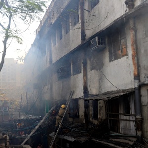 Curiosos observam bombeiro que tenta combater incêndio no mercado Surya Sen, em Calcutá (Índia). O fogo atingiu os seis andares do prédio - Dibyangshu Sarkar/AFP
