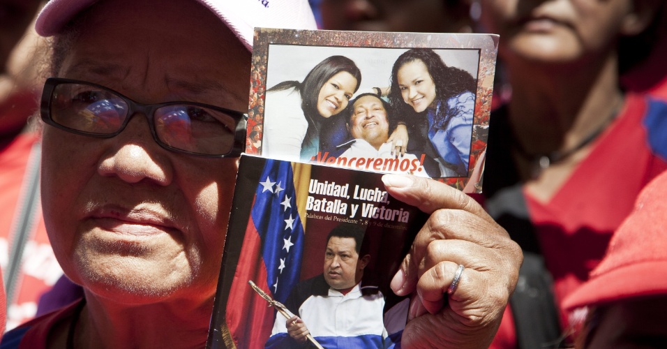 4.mar.2013 - Mulher segura foto do presidente da Venezuela, Hugo Chávez, durante missa celebrada hoje na Praça de Bolivar de Caracas, na Venezuela, pela saúde do presidente.