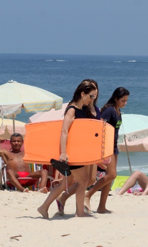 9.mar.2013 - Acompanhada das filhas, Cláudia Abreu aproveita o calor para praticar bodyboard em praia do Leblon, no Rio