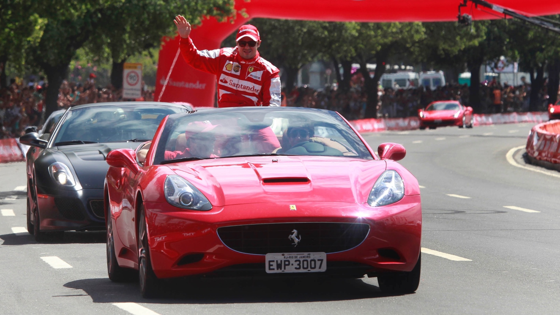 10.mar.2013 - Felipe Massa é levado por uma Ferrari e acena para o público carioca que acompanhou sua passagem dirigindo um veículo da escuderia pela cidade - Marco Antônio Teixeira/UOL