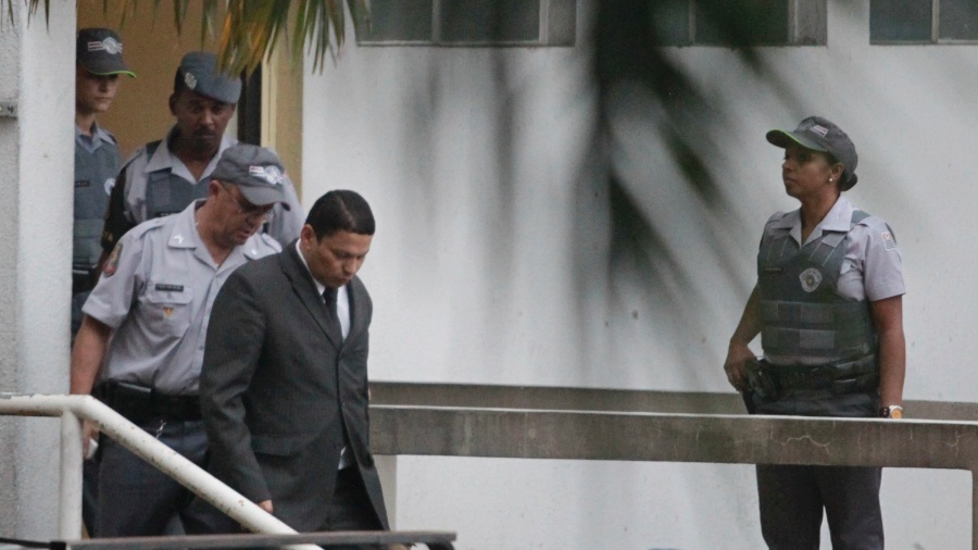 14.mar.2013 - O policial reformado Mizael Bispo da Silva (de paletó) deixa o Fórum de Guarulhos (SP) escoltado por policiais após ser condenado a 20 anos de prisão pelo assassinato da ex-namorada, a advogada Mércia Nakashima, ocorrido em 23 de maio de 2010 - Fernando Donasci/UOL