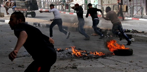 Palestinos correm pela região central de Hebron, na Cisjordânia, durante confronto da polícia fronteiriça de Israel com manifestantes contrários à expansão de assentamentos judaicos  - 15.mar.2013 -  Hazem Bader/AFP