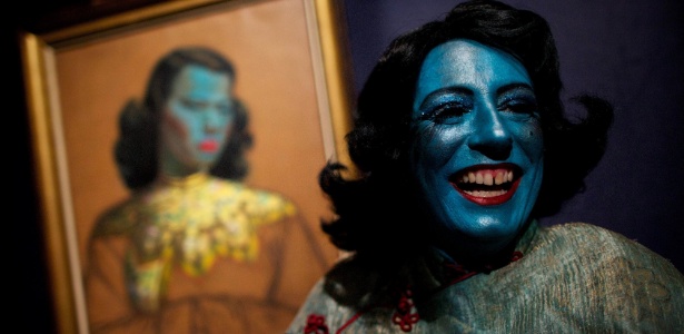 Cantora de cabaret Tricity Vogue, se veste como a personagem senhora azul, inspirada na pintura "Menina Chinesa" (ao fundo), do artista Vladimir Tretchikoff, na casa de leilões Bonhams, em Londres, no Reino Unido - Andrew Cowie/AFP