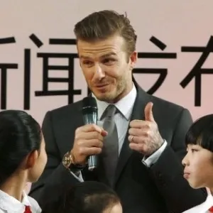 20.mar.2013 - David Beckham é cercado por crianças durante evento em Pequim - How Hwee Young/EFE
