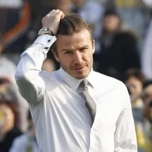 20.mar.2013 - David Beckham não perde a pose e ajeita o cabelo enquanto joga bola com garotos na China - How Hwee Young/EFE