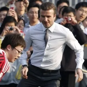 20.mar.2013 - Gravata e sapatos sociais não foram problema para David Beckham jogar bola com estudantes chineses - How Hwee Young/EFE