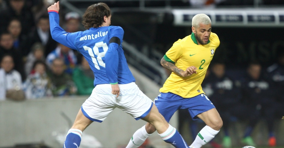 21.mar.2013 - Com o cabelo loiro, Daniel Alves tenta fugir da marcação de Montolivo no amistoso entre Brasil e Itália