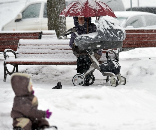 22.mar.2013 - Criança brinca perto da mãe durante nevasca em parque de Kiev, capital da Ucrânia