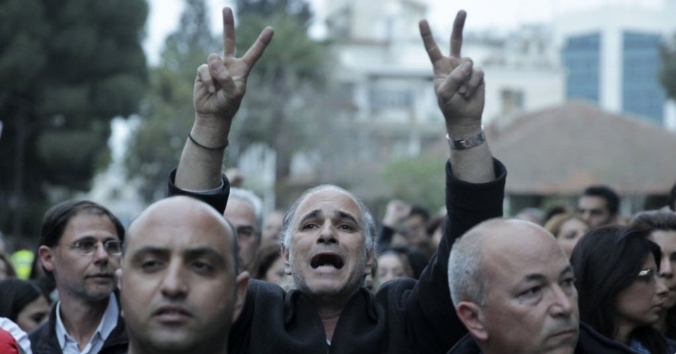 22.mar.2013 - Manifestante cipriota faz sinal de vitória durante protesto de quinta-feira (21) em frente ao Parlamento do Chipre, em Nicósia, capital do país