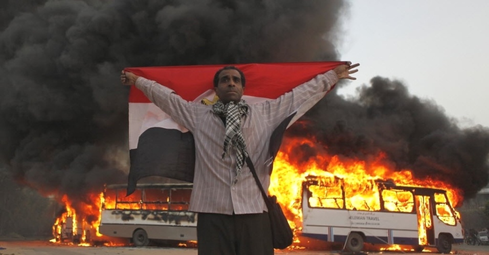 22.mar.2013 - Manifestante egípcio exibe bandeira do país durante protestos em que ônibus da Irmandade Muçulmana, que governa o país, foram incendiados, no bairro de Moqattam, no Cairo