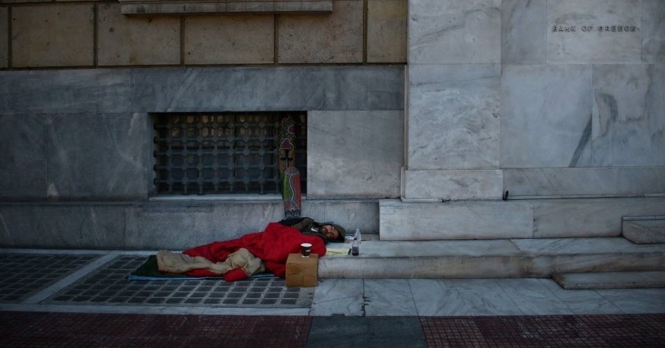 22.mar.2013 - Morador de rua dorme ao lado da entrada da sede do Banco da Grécia, em Atenas