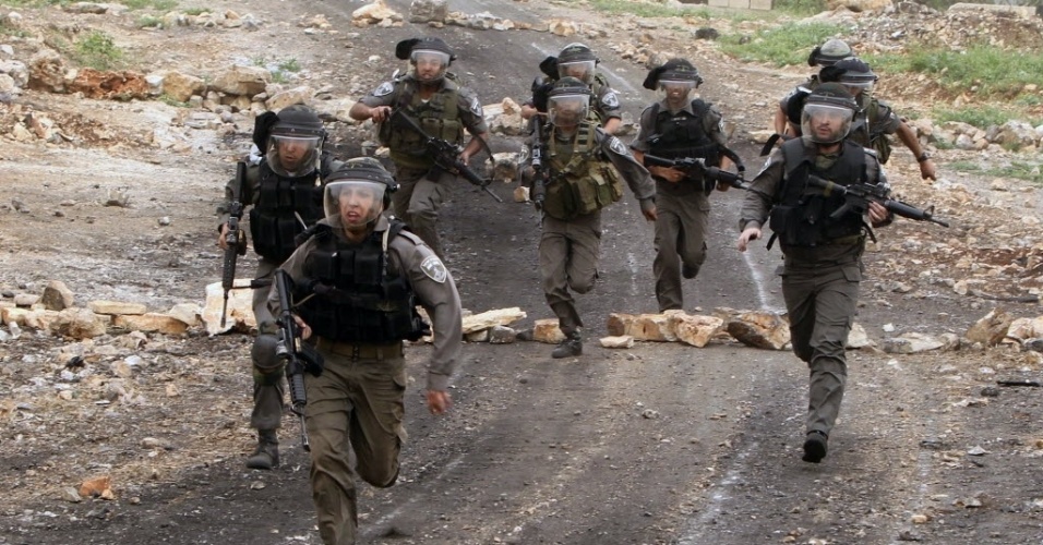 22.mar.2013 - Policiais de fronteira israelenses correm atrás de manifestantes durante protesto de palestinos contra a expansão de assentamentos judaicos na vila de Kafr Qaddum, na Cisjordânia