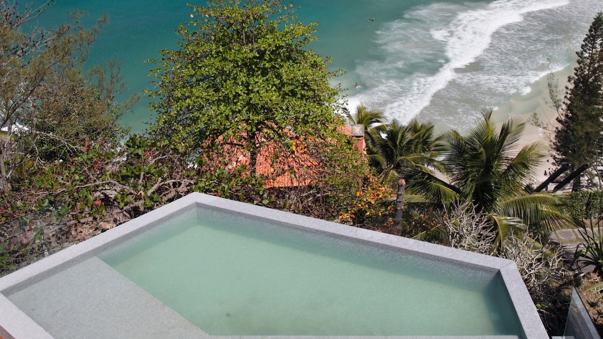 A Casa do Joá, com reforma projetada pelo escritório House in Rio, possui piscina em formato hexagonal com borda infinita que parece uni-la ao mar, formando um quadro de grande beleza. A construção está localizada em um aclive na praia da Joatinga, no Rio de Janeiro - Denilson Machado/ MCA Studio/ Divulgação