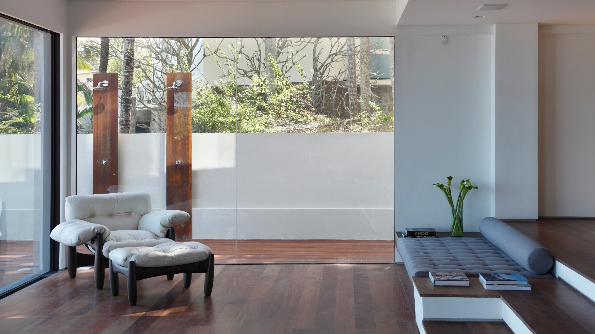 A integração interior/exterior permite que os moradores desfrutem da piscina e, antes de entrar na casa, tomem uma ducha nos chuveiros instalados no corredor lateral. A poltrona Mole, de Sergio Rodrigues, compõe o ambiente de estar, com poucos móveis. A Casa do Joá tem reforma assinada pelo escritório House in Rio - Denilson Machado/ MCA Studio/ Divulgação
