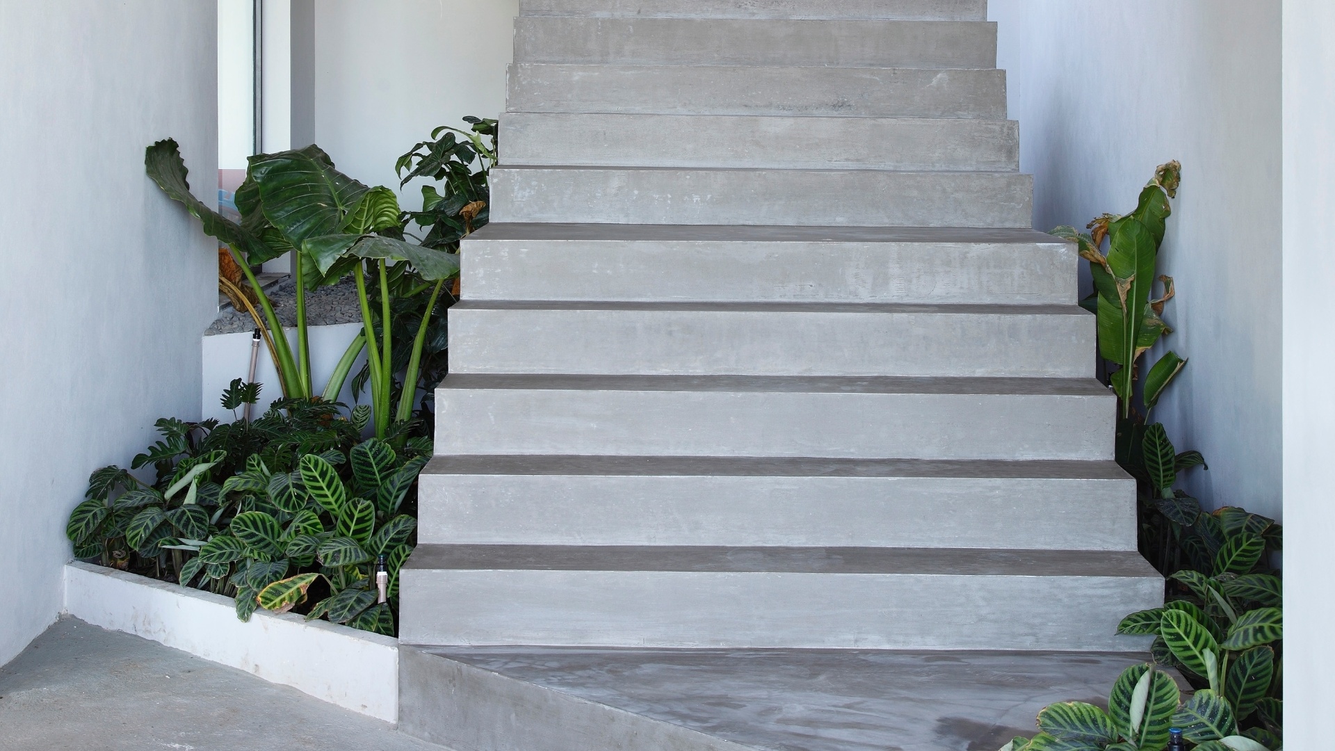 Com estrutura de metal e concreto, a escada escultórica é o detaque do hall de entrada e liga o primeiro ao segundo pavimento. A Casa do Joá, com projeto de reforma do escritório House in Rio, tem paisagismo da Embya - Denilson Machado/ MCA Studio/ Divulgação