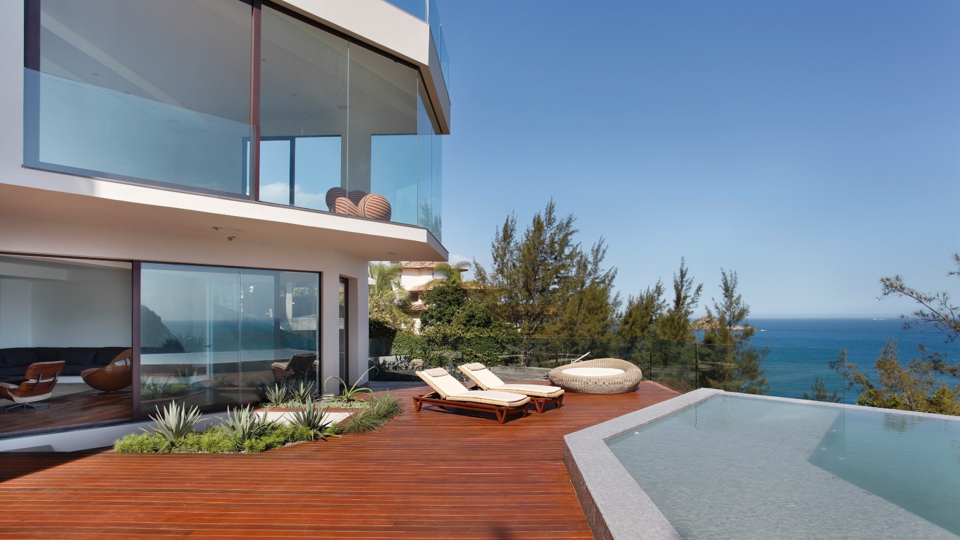 Com projeto de reforma do escritório House in Rio, a Casa do Joá tem quatro pavimentos, todos com fechamento em vidro para que os moradores possam desfrutar da paisagem litorânea. No segundo andar, a piscina com revestimento em pastilhas de vidro, Vidrotil, tem borda infinita e deck com espreguiçadeiras da Saccaro - Denilson Machado/ MCA Studio/ Divulgação
