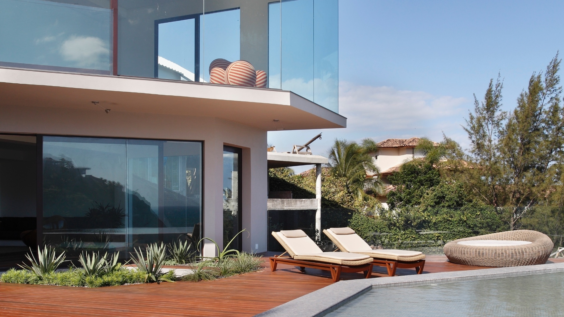 Com projeto de reforma do escritório House in Rio, a Casa do Joá tem quatro pavimentos, todos com fechamento em vidro para que os moradores possam desfrutar da paisagem litorânea. No segundo andar, a piscina com revestimento em pastilhas de vidro, Vidrotil, tem borda infinita e deck com espreguiçadeiras da Saccaro - Denilson Machado/ MCA Studio/ Divulgação