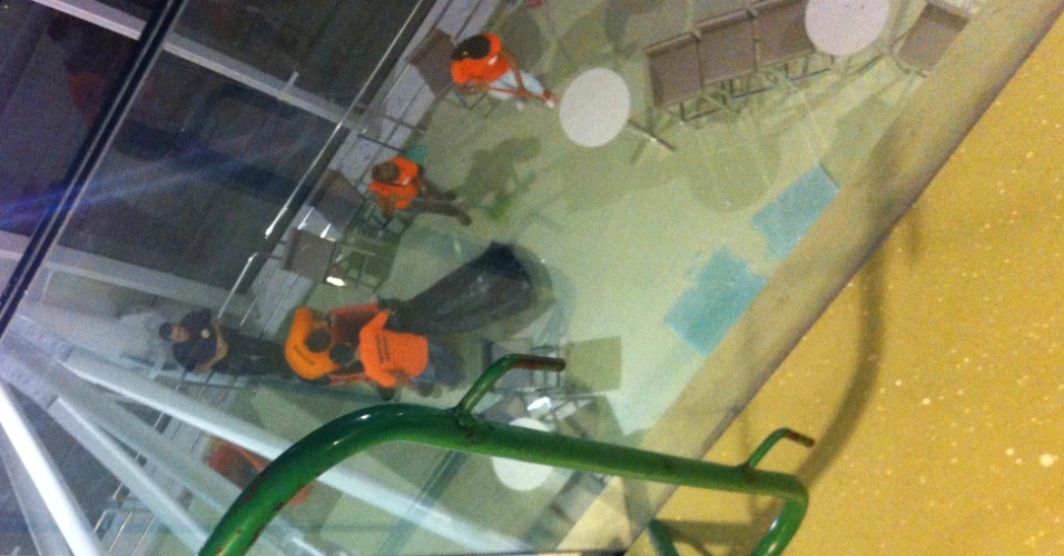 Funcionários recolhem cacos de vidraça que caiu de uma altura de 10 metros no Castelão, em Fortaleza