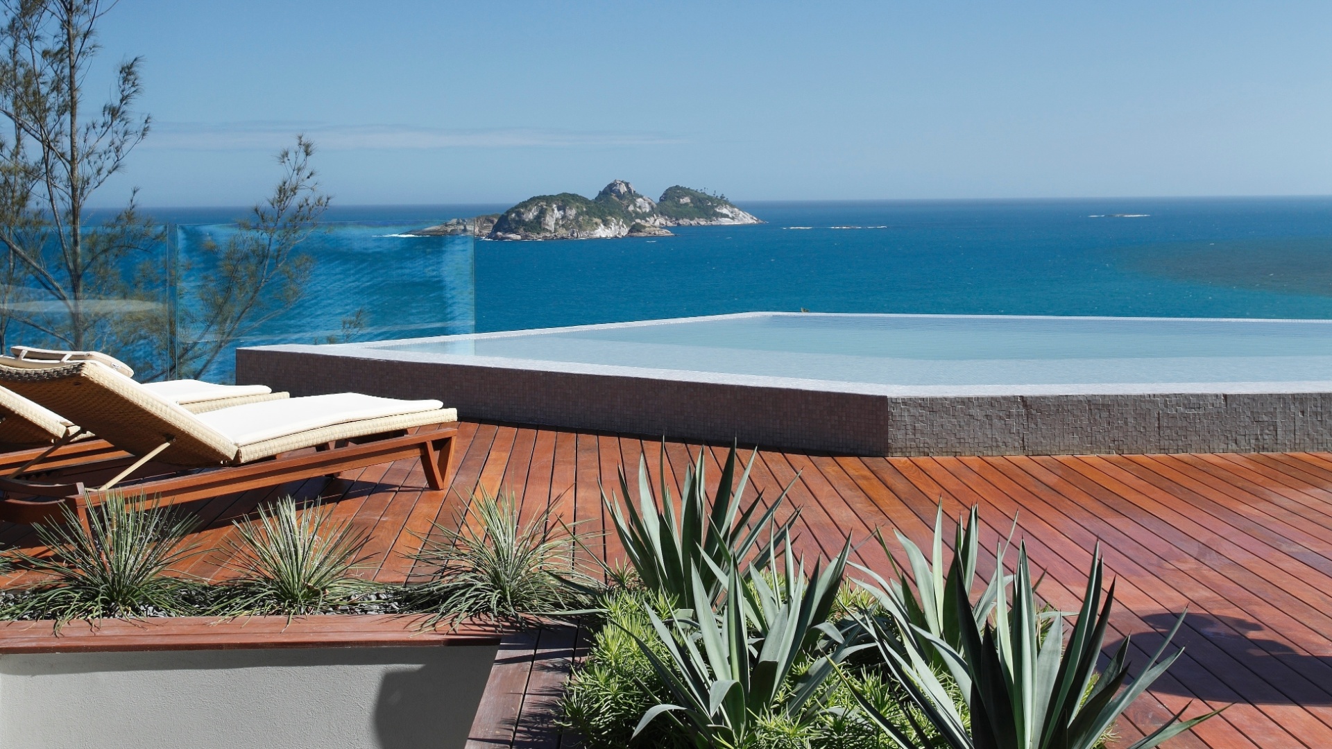 Para os banhos de sol foram dispostas, bem perto da piscina, as espreguiçadeiras da Saccaro. O paisagismo da Embya compõe com a paisagem que circunda a casa do Joá, no Rio de Janeiro. O projeto de reforma é do escritório House in Rio - Denilson Machado/ MCA Studio/ Divulgação