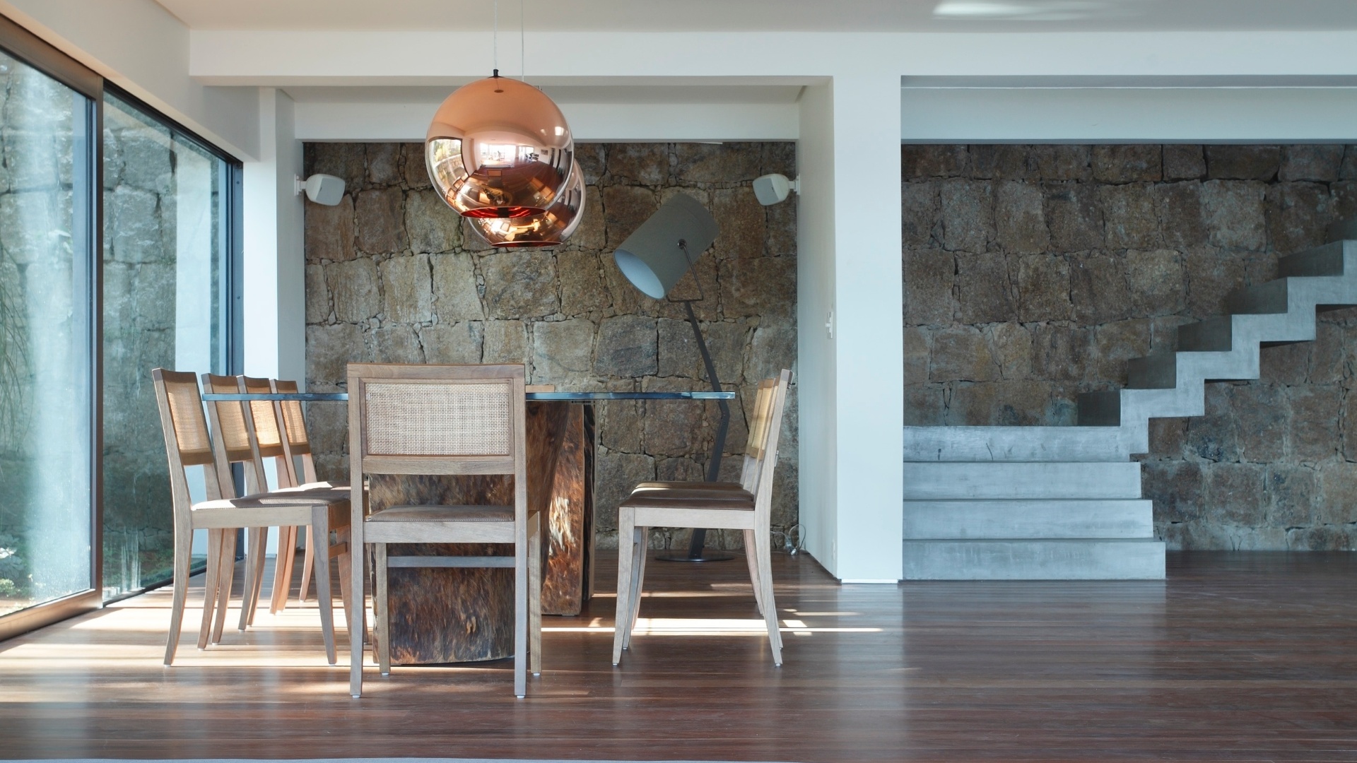 Um pequeno desnível de três degraus separa as salas de jantar e estar que tem sofás de alvenaria e rolos estofados como apoios, possibilitando o "relax" total e a visualização completa da paisagem. A Casa do Joá tem projeto de reforma do escritório House in Rio e fica na Praia da Joatinga, Rio de Janeiro - Denilson Machado/ MCA Studio/ Divulgação