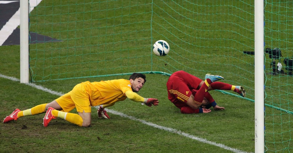 26.mar.2013 - Com Pedro caído no gol, o goleiro Hugo Lloris, da França, tenta tirar a bola com um tapa, mas não consegue impedir o gol espanhol