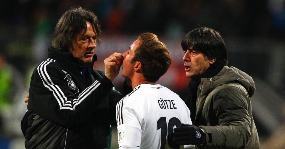 26.mar.2013 - Meia alemão Mario Goetze é atendido pelo médico da Alemanha e ouve instruções de Joachim Loew durante a partida contra o Cazaquistão