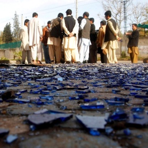 Pessoas se reúnem próximo a cacos de vidro, quebrados por explosão à bomba em ataque suicida em Jalalabad (Afeganistão)