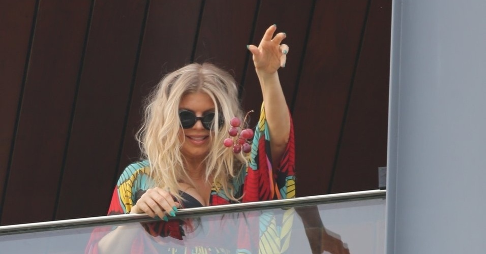 4.abr.2013 - Fergie joga cacho de uvas para seus fãs no hotel Fasano, no Rio de Janeiro. A cantor está na capital carioca a convite da grife Hugo Boss