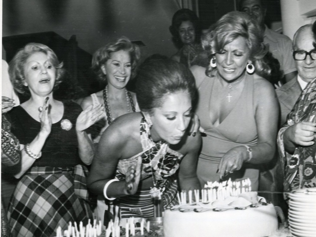 A atriz Ceyde Yáconis (segunda, da esquerda para a direita) bate palmas durante o aniversário de Lolita Rodrigues em 1975. Ao lado, a apresentadora Hebe Camargo - Folhapress