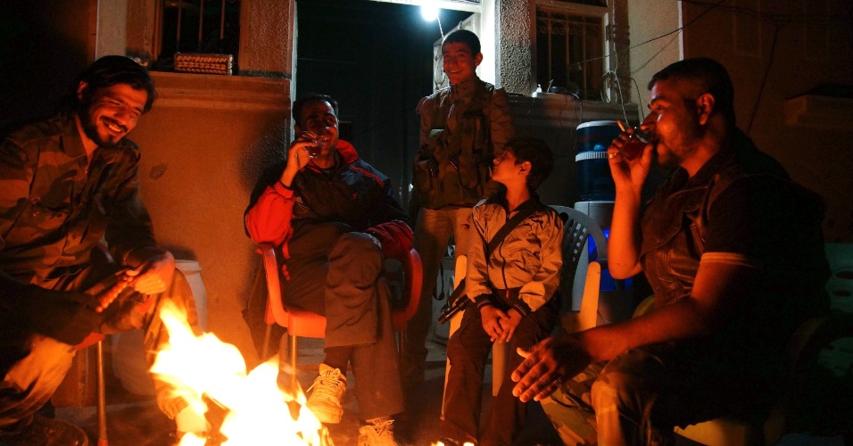 19.abr.2013 - Membros do Exército Livre da Síria tomam chá enquanto sentam envolta de uma fogueira em Deir al-Zor, na Síria