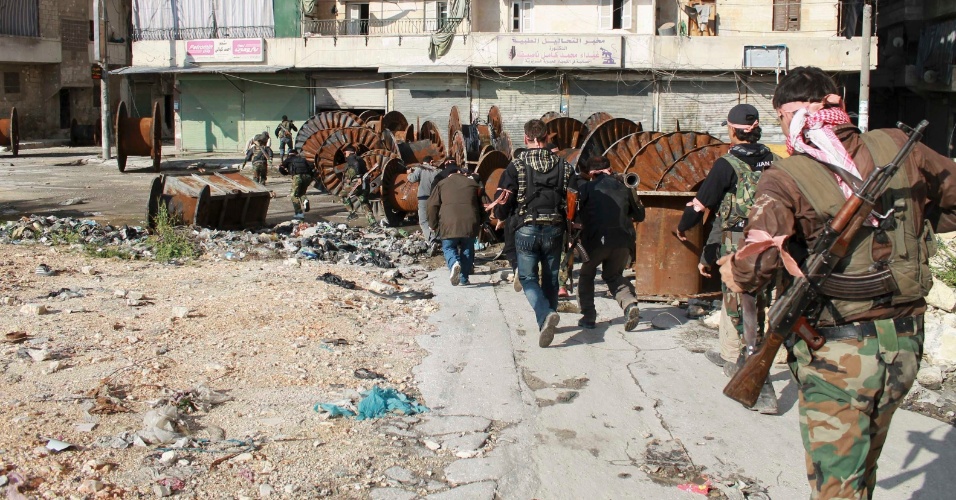 21.abr.2013 - Combatentes do Exército Livre da Síria carregam armas enquanto caminham para tomarem posição durante uma operação no bairro de Salaheddine, em Aleppo, na Síria
