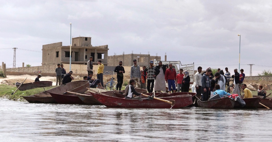 21.abr.2013 - Refugiados sobem em barco para acessar a cidade de Deir Al-Zor, na Síria