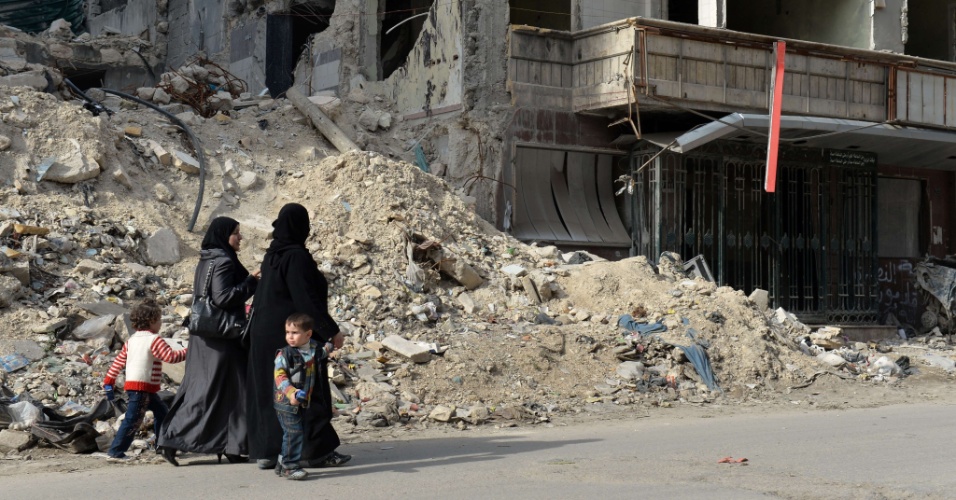 22.abr.2013 - Mulheres sírias passam por um hospital destruído em Dar Al-Shifa, no norte de Aleppo, na Síria