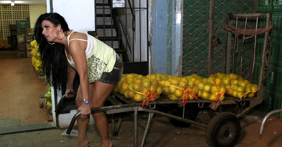 22.abr.2013 - Solange Gomes tenta carregar sacos de laranja no Cadeg, no Rio de Janeiro. A modelo viveu um dia de carregador de laranjas para o "Programa da Tarde", da Record