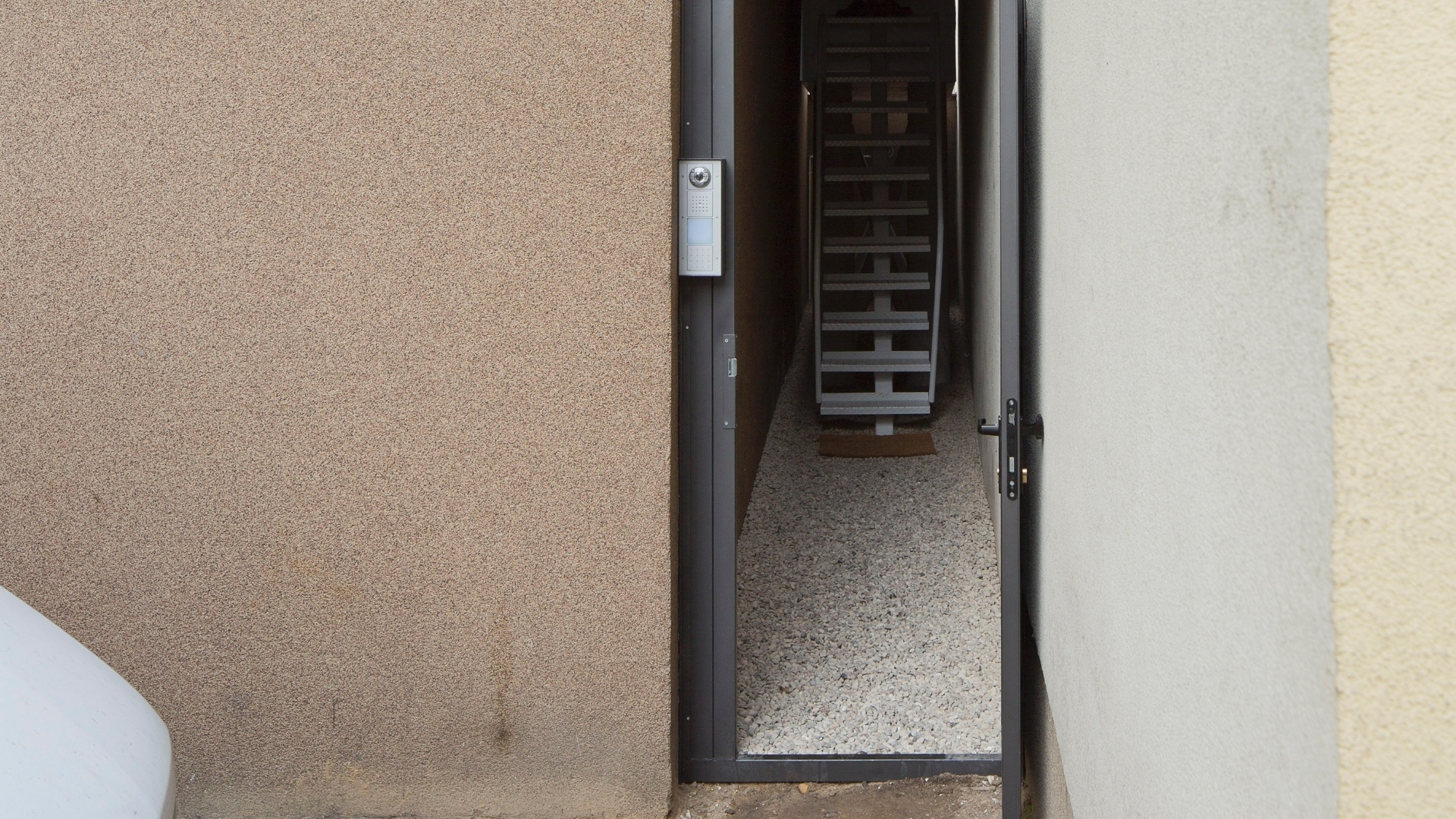 A porta de metal e um caminho de cascalho que conduzem à entrada da Casa Keret, em Varsóvia, Polônia - Andrea Meichsner/The New York Times