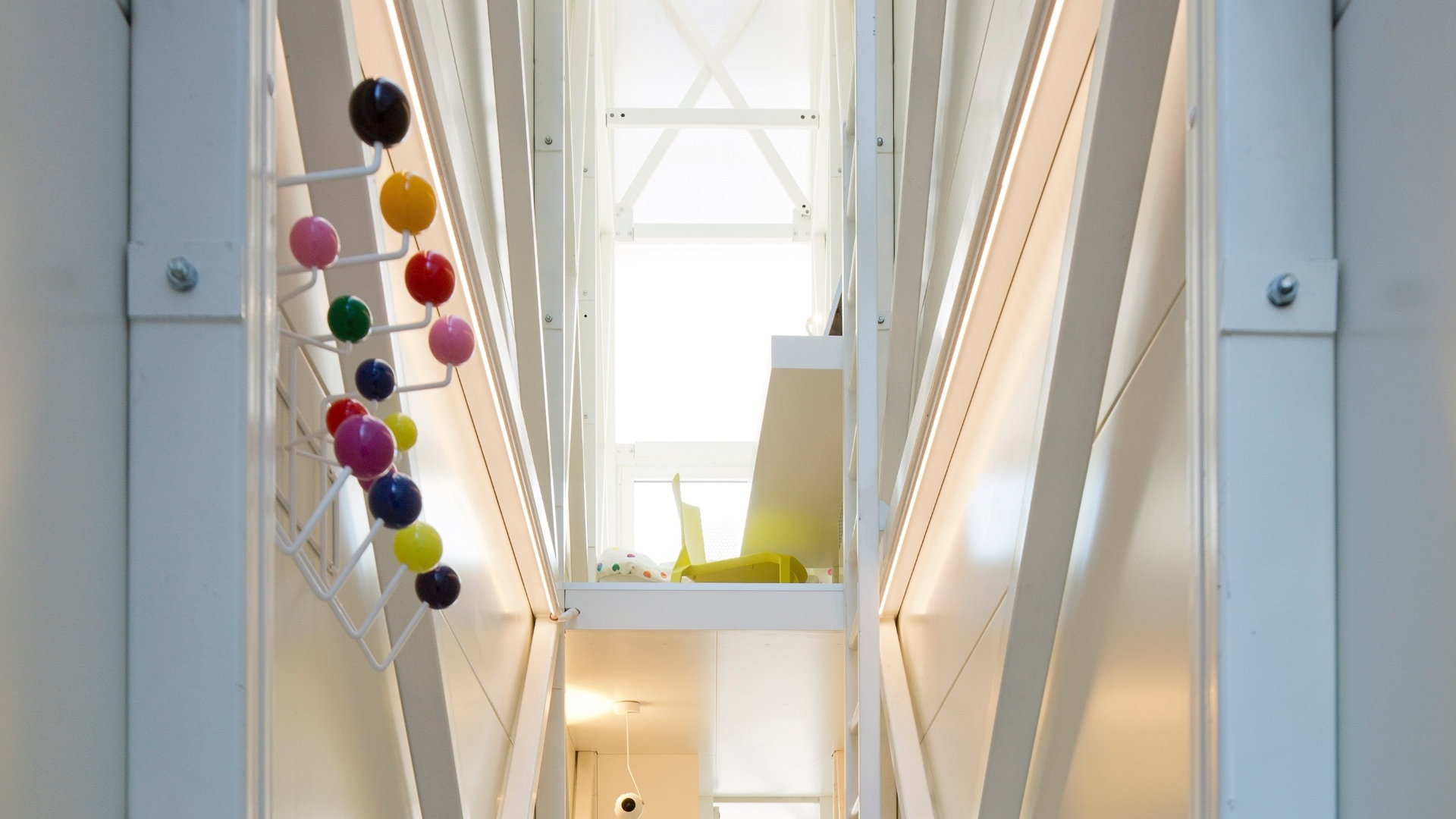 Na sala de estar da Casa Keret, destaque para o alcapão que leva ao andar inferior e o cabide que acrescenta pontos de cor para o interior todo branco. A pequena casa está "espremida" no espaço entre dois prédios em Varsóvia, Polônia - Andrea Meichsner/The New York Times