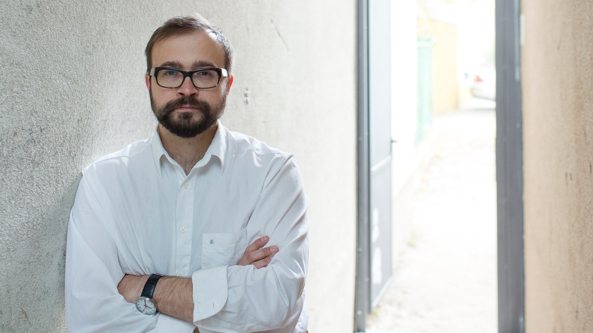 O arquiteto polonês, Jakub Szczesny, em frente ao beco sob a Casa Keret, em Varsóvia, Polônia. Projetada por ele, a residência com 71cm de largura na sua parte mais estreita está entre um edifício pré-guerra e um conjunto habitacional pós-guerra de onze andares - Andrea Meichsner/The New York Times