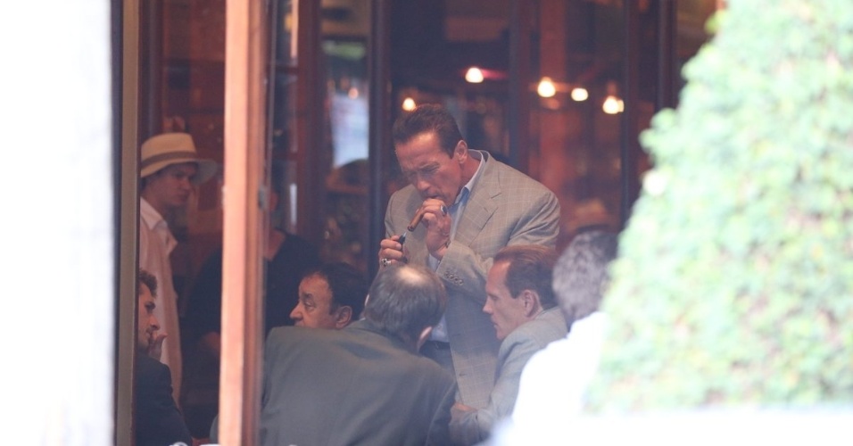 25.abr.2013 - Arnold Schwarzenegger fuma charuto em cafeteria na zona sul do Rio de Janeiro. O ator está na cidade para participar de um evento de fisiculturismo
