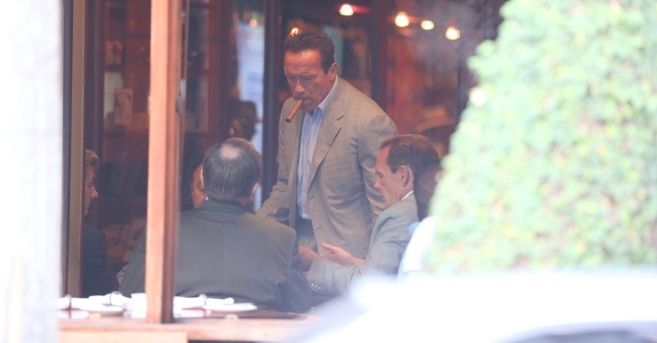 25.abr.2013 - Arnold Schwarzenegger fuma charuto em cafeteria na zona sul do Rio de Janeiro. O ator está na cidade para participar de um evento de fisiculturismo