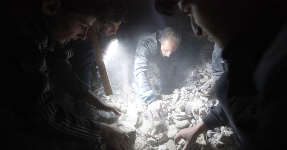 25.abr.2013 - Sírios usam lanternas para procurar sobreviventes em área danificada pelo que ativistas disseram ser um ataque de míssil feito pelo regime sírio, na província de Raqqa, no leste da Síria, nesta quinta-feira (25)