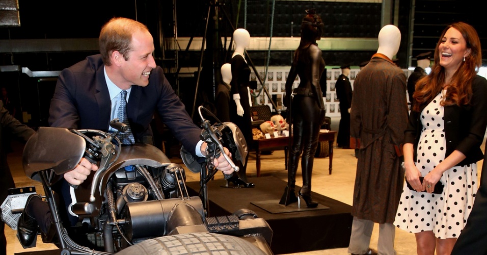 26.abr.2013 - Príncipe William monta na moto usada por Anne Hathaway em "Batman - O Cavaleiro das Trevas Ressurge" e Kate Middleton se diverte ao ver a cena. O casal real estava em visita aos estúdios Warner Bros Leavesden, em Londres